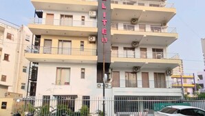 A multi-story building with balconies, a sign reading 'ELITE,' and parked motorcycles and a car in front. - Hotel Elite One (Gurugram)