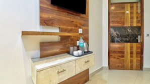 Un baño moderno con tocador de madera, televisor montado y puerta con incrustación de mármol.