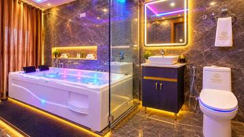 Une salle de bain moderne avec un jacuzzi entouré de parois en verre, un meuble-lavabo et des toilettes.