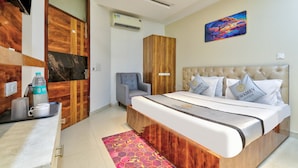Una habitación de hotel con una cama, una silla, un escritorio y una botella de agua, además de un cuadro en la pared.