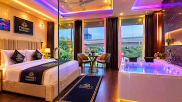 A TWAMEV RESIDENCY hotel room with a bed, a desk, a chair, a large window, and a jacuzzi.