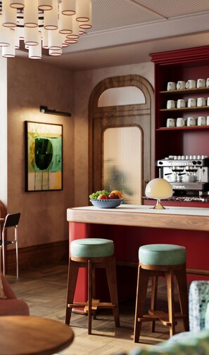 A kitchen with a bar area, stools, a coffee machine, and a fruit bowl. - The July - Capel Street (Dublin)