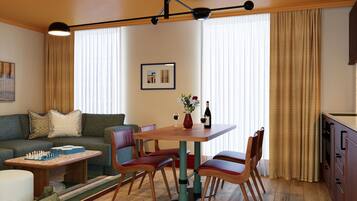 Een gezellig, ruimtelijk ingerichte leefruimte met een eettafel, stoelen, een bank, een klein bijzettafeltje en een keukenhoek.