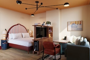 Una habitación de hotel con cama, escritorio, silla, televisor y sofá.