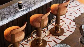 Un coin bar avec trois tabourets, un comptoir en marbre et un sol à motifs.