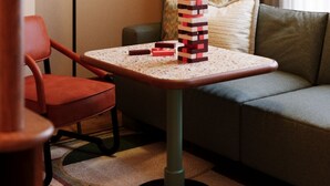 Una habitación de hotel con un sofá, una mesita con lámpara y una pila de bloques.