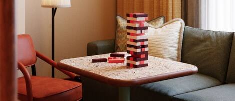 A hotel room with a sofa, a small table with a lamp, and a stack of blocks.
