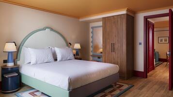 A bedroom with a bed, nightstands, a wardrobe, and a door leading to another room.