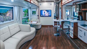 A modern interior with a sofa, a TV, a small table, and a kitchen area. - YAOJIA YANGXIN RESORT (Shaoxing)