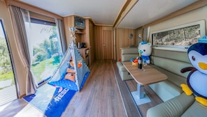 A cozy RV interior with a dining area, a sleeping section, and a view of the outdoors. - YAOJIA YANGXIN RESORT (Shaoxing)