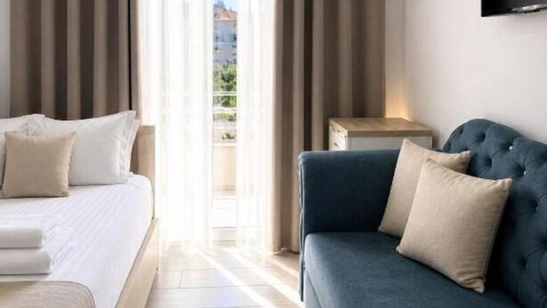 Camera d'albergo con un letto, una poltrona, una TV a parete e vista dalla finestra.