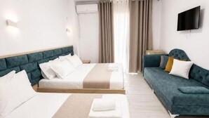Una camera d'albergo con due letti, un divano, una TV a schermo piatto e un condizionatore.