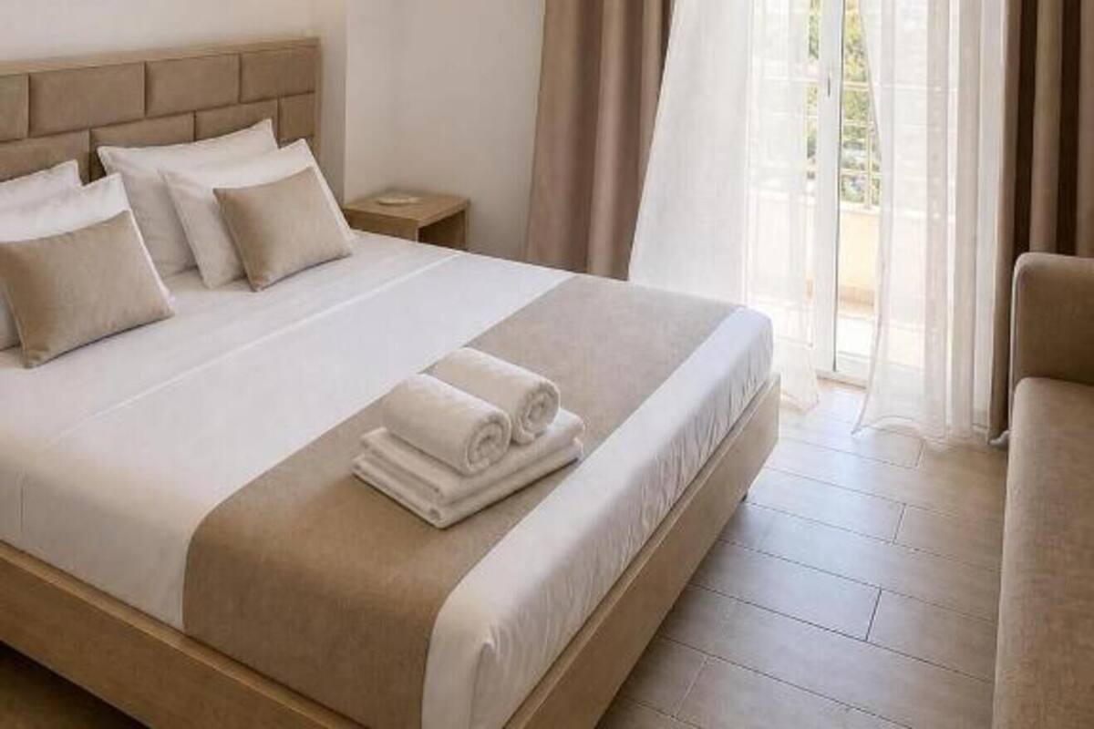 Habitación de hotel con cama, mesita de noche, equipo de aire acondicionado y vista por la ventana.