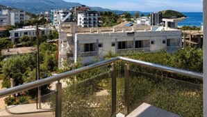 Un balcone con vista su una cittadina costiera, edifici e montagne.