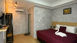 Ein Hotelzimmer mit einem Bett, einem Schreibtisch, einer Klimaanlage und einem Bild an der Wand.