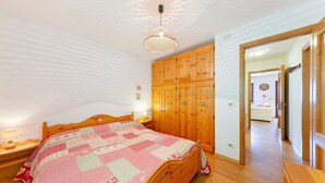 Quarto com cama de madeira, guarda-roupa de madeira e luminária no teto.