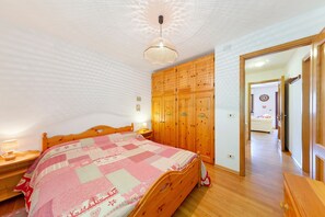 A bedroom with a wooden bed, a wooden wardrobe, and a ceiling light fixture. - Apartment 'Casa Fiori a Vinigo' with Mountain View and Balcony (Vinigo)