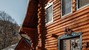 Une cabane en rondins avec un escalier en pierre menant à l’entrée, des portes et des fenêtres en bois.