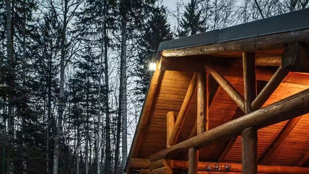 Une cabane en rondins avec un mur en pierre et une terrasse en bois.