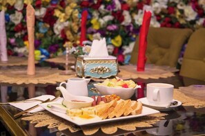 Ein Tisch gedeckt mit einer Kaffeetasse, Obstschale, Brotplatte und einer Taschentuchbox.