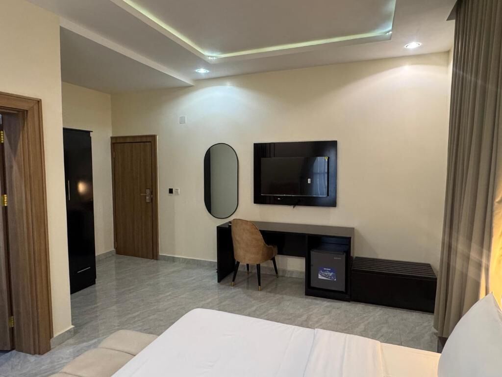 Une chambre d’hôtel moderne équipée d’un lit, d’un bureau avec une chaise, d’une télévision et d’un miroir.