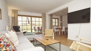 Een moderne woonkamer met een bank, salontafel en een eethoek met stoelen en een tafel.