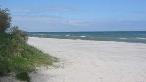 Een strand met een heldere lucht en een rustige zee.