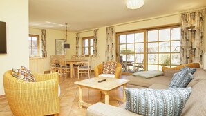 A living room with a sofa, chairs, a table, and a TV. - Modern and comfortable vacation home - Reethaus Wiek left half of the house (Wiek)