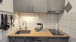 Ett kompakt kök med en diskho i rostfritt stål, en kaffebryggare och ett knivställ.