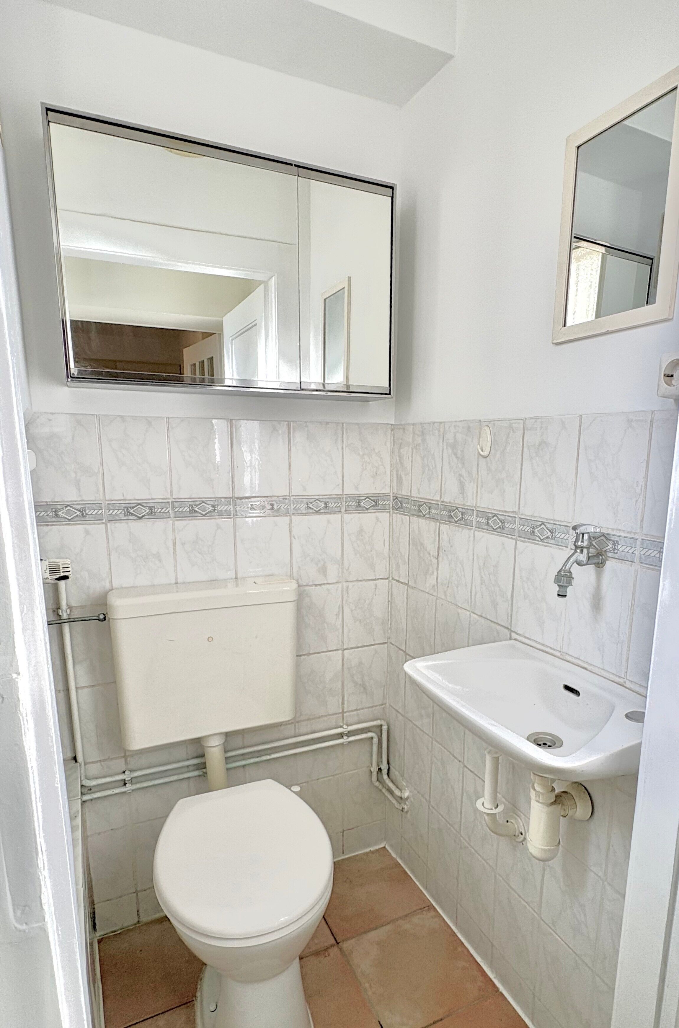 Une salle de bain avec des toilettes, un lavabo et un miroir.