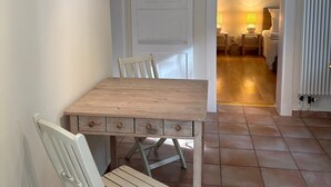 En matplats med ett träbord och stolar, en vit dörr och ett klinkergolv.