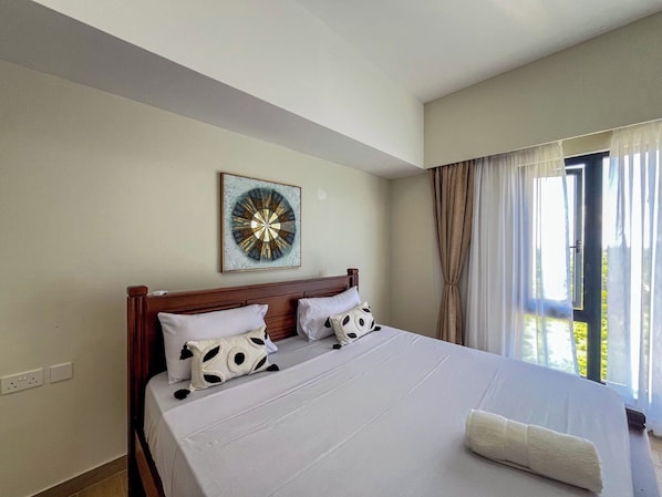 Habitación de hotel con una cama grande, una obra de arte en la pared y una ventana con cortinas.