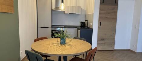 Une cuisine moderne dotĂ©e dâun Ăźlot central, dâun coin repas avec une table ronde et dâune porte coulissante donnant sur une autre piĂšce.