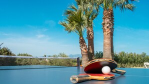 A table tennis table with a ball and paddle, surrounded by palm trees. - 283 Can Joan Verdal by Mallorca Charme (Muro)