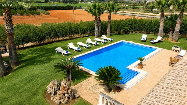 A swimming pool with lounge chairs, palm trees, and a view of mountains. - 283 Can Joan Verdal by Mallorca Charme (Muro)