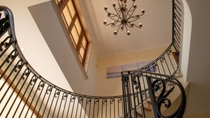 A curved staircase with ornate metal railings and a chandelier. - 283 Can Joan Verdal by Mallorca Charme (Muro)