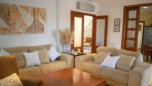A living room with two beige sofas, a wooden coffee table, and a large abstract painting on the wall. - 283 Can Joan Verdal by Mallorca Charme (Muro)
