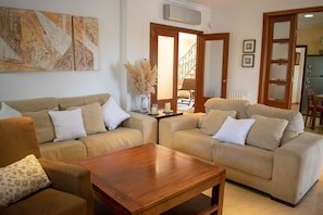 A living room with two beige sofas, a wooden coffee table, and a large abstract painting on the wall. - 283 Can Joan Verdal by Mallorca Charme (Muro)