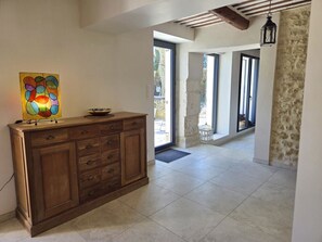 A hallway with a wooden cabinet, a stained glass window, and a stone wall. - Le Mascalis | Large family home in Provence (L`Isle-sur-la-Sorgue)