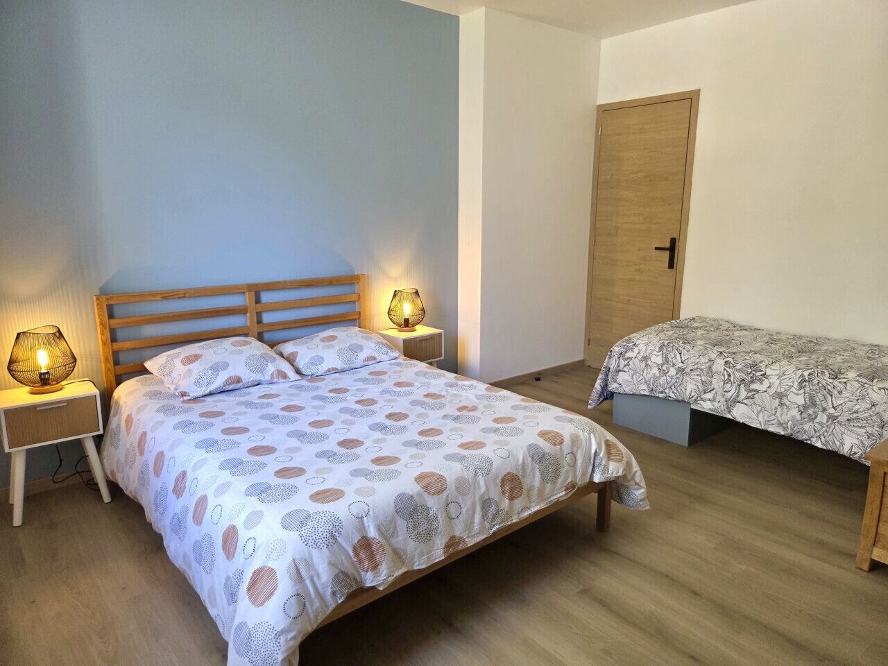 A bedroom with a bed, bedside tables, a nightstand, a wardrobe, and a bench.