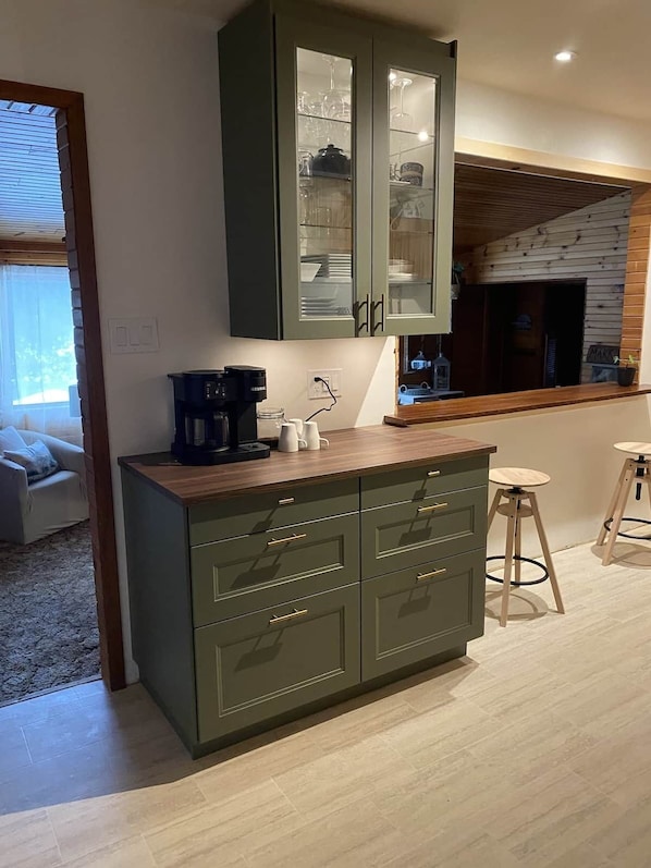 A kitchen with a built-in cabinet, a coffee machine, and a small stool.