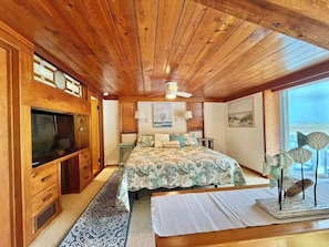 Interno di una baita in legno con un letto, una televisione e opere d'arte alle pareti.