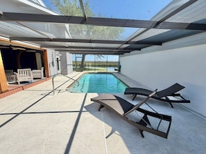 Area piscina esterna coperta con lettini, un solarium in legno e vista su un paesaggio naturale.