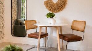 Un área de comedor con una mesa redonda, dos sillas y decoración en la pared.