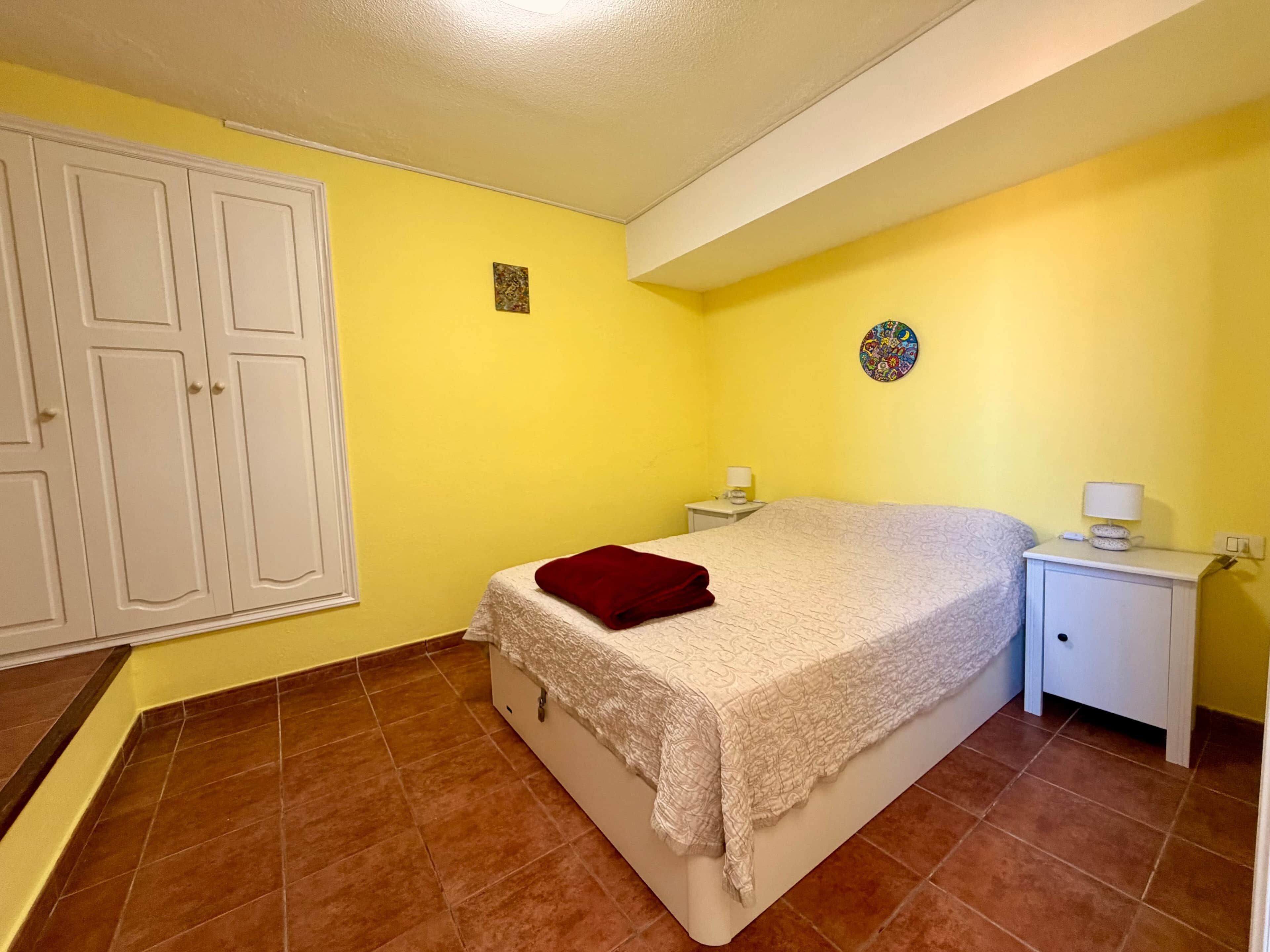 Een slaapkamer met een bed, nachtkastjes, een kledingkast en een wandklok.