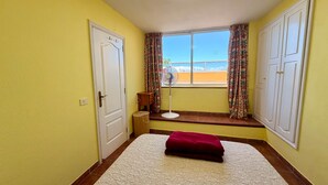 A room with a bed, a window with curtains, a fan, and a door. - 2 BD Apartment with stunning view (Acantilados de los Gigantes)