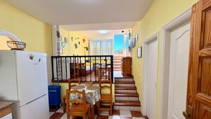A compact kitchen with a Bosch refrigerator, wooden chairs, a dining table, and a staircase leading to a bedroom. - 2 BD Apartment with stunning view (Acantilados de los Gigantes)