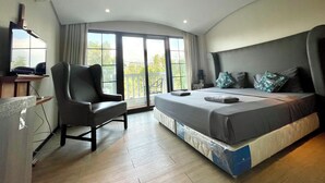 Een slaapkamer met een groot bed, een stoel, een televisie en een balkon met uitzicht.