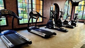 Een sportschool met een rij loopbanden, elliptische trainers en hometrainers.