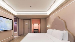 Habitación de hotel con una cama grande, un televisor de pantalla plana montado en la pared, una mesita de noche y una mesilla.